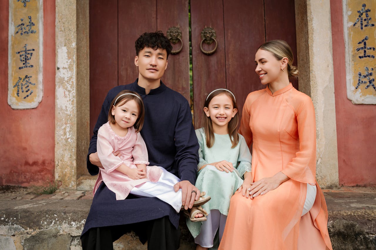 A family sits together in traditional Vietnamese áo dài at a historic site in Hội An.